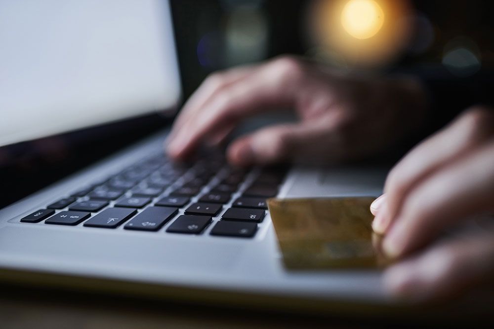 Hands typing on a laptop keyboard with a credit card, depicting online shopping or secure payment.