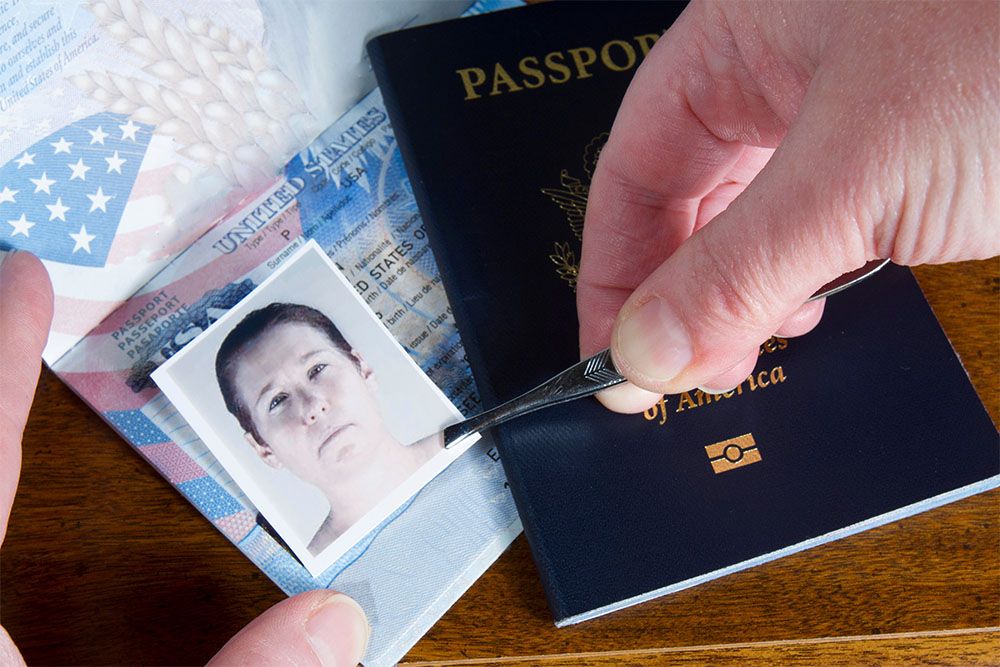 Person swapping a passport photo with tweezers, suggesting identity fraud or travel document tampering.