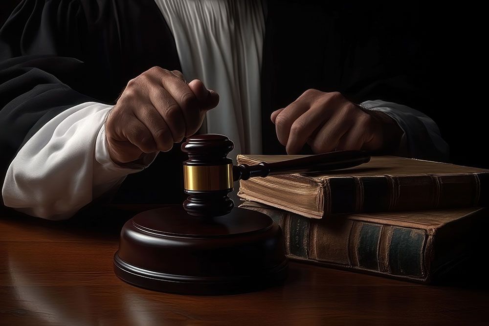 Judge holding gavel beside law books, symbolizing justice and legal proceedings in a courtroom setting.