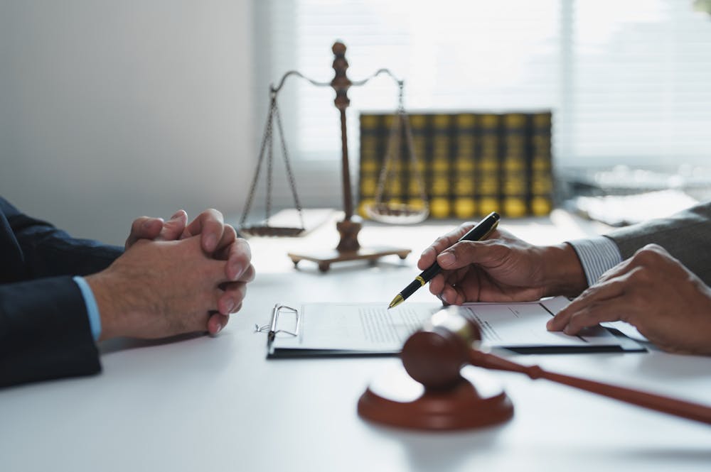 Lawyer consulting client with legal documents, gavel, and scales in office setting.