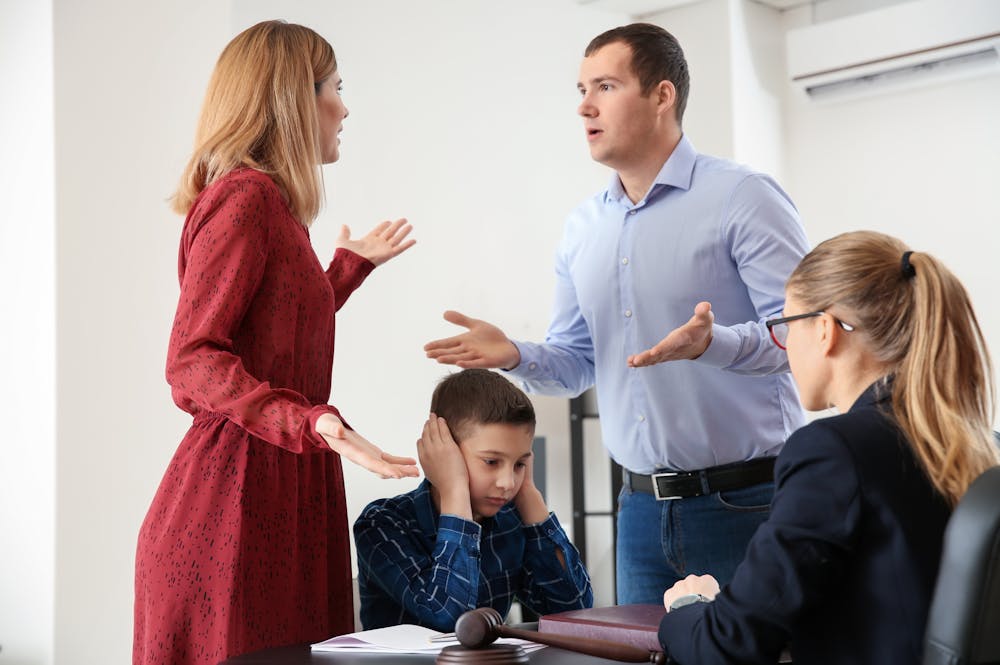 Couple arguing in front of a child and a mediator during a meeting, illustrating family conflict resolution.